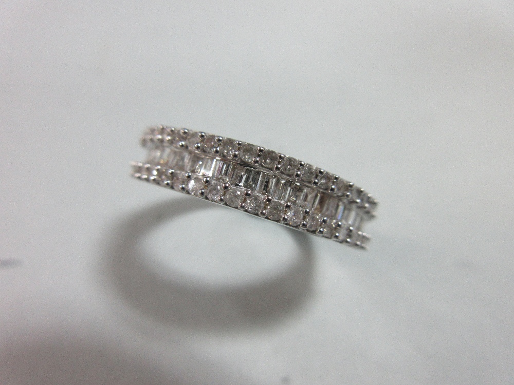 A diamond and white gold half band ring, with a channel set line of baguette cut diamonds between