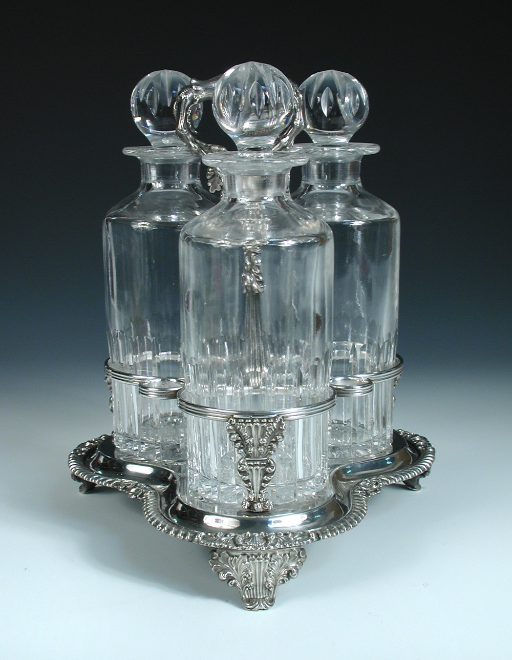 An early Victorian Old Sheffield plate three bottle decanter stand, the trefoil base having three