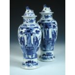 A pair of 19th century Chinese blue and white baluster vases and covers, each painted with pairs