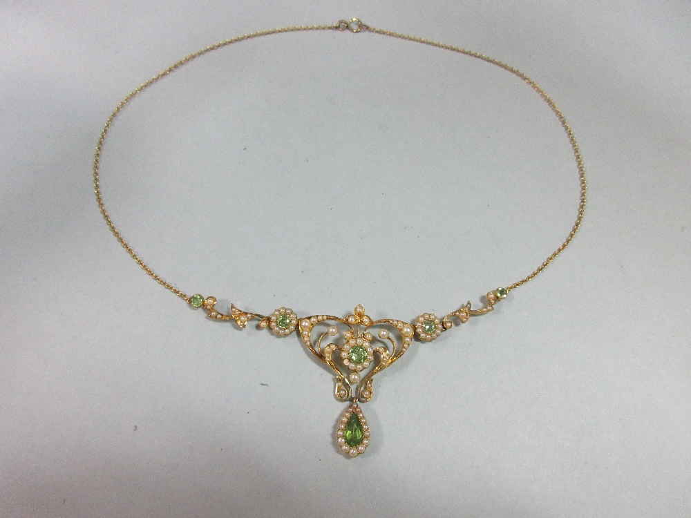 An Edwardian peridot and pearl necklace, the central art nouveau style motif set with a round cut