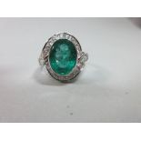 An oval emerald and diamond ring, the large oval cut emerald, measuring 12 x 9mm, collet set at an