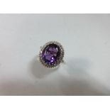 An amethyst and diamond ring, the oval mixed cut amethyst of good colour, claw set in a border of