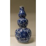 A 19th century Chinese blue and white triple gourd vase painted overall with scrolling lotus, the