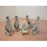 Three Polonnoe ladies, each seated wearing ice skates, 16cm high, a figure of a skier, 15cm high and