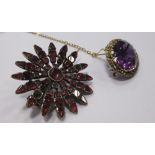 A foil backed ruby flowerhead brooch, the round central stone surround by tapered petals