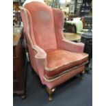 A salmon pink covered wing armchair