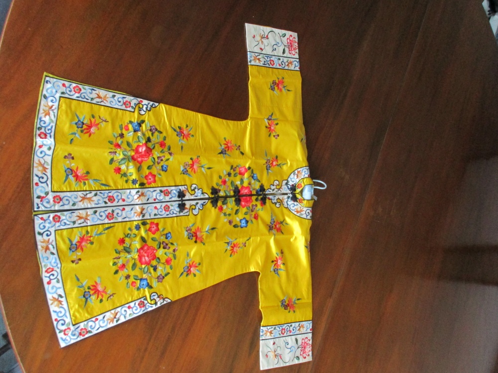 A Chinese lady's silk yellow ground robe embroidered with coloured flowers, the length from collar