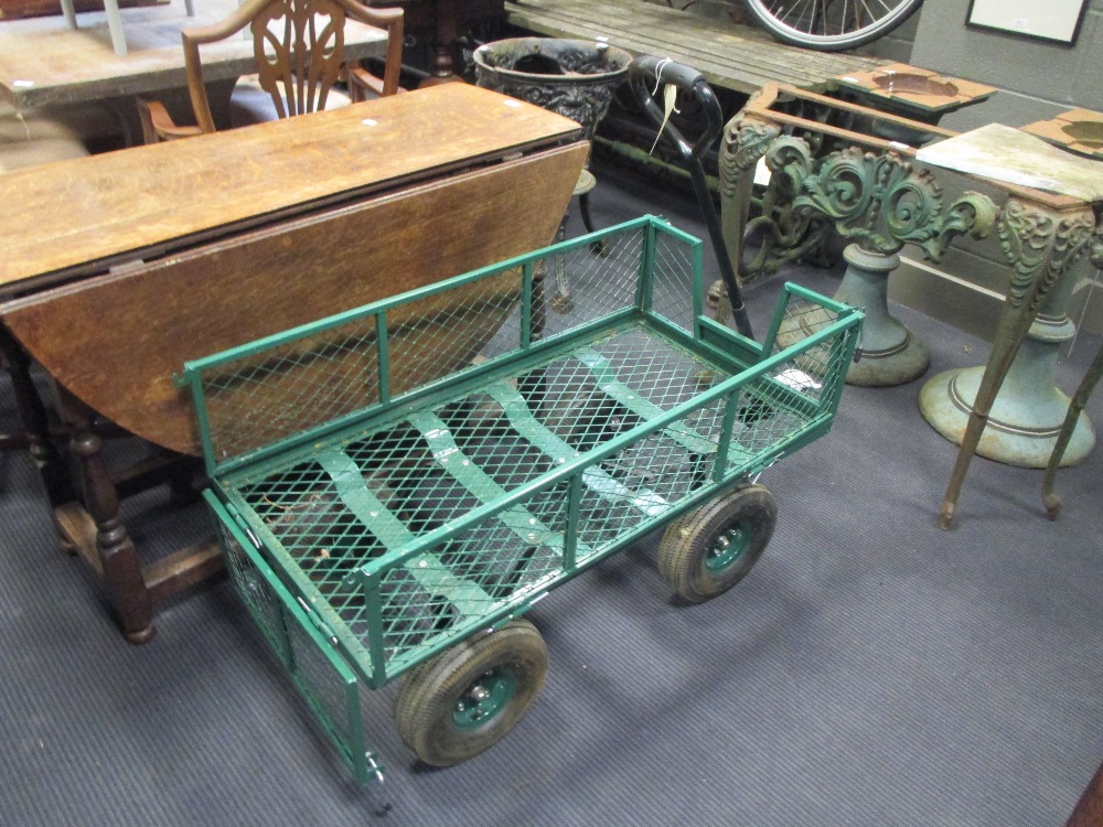 A wirework green painted trolley with handle and drop down sides