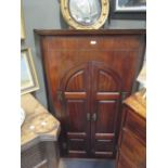 A George III mahogany corner cupboard, with arched panelled doors and shaped shelved interior,