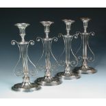 A set of four Old Sheffield plate candlesticks, each with lyre stem over an oval fan fluted base,