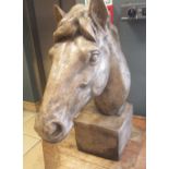 A reconstituted stone sculpture of a horse's head with flowing mane on a square plinth base, 62cm