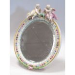 A German porcelain easel mirror surmounted with putto