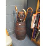 An oak bound barrel with side handles holding various walking sticks