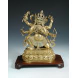 A Tibetan gilt bronze figure of the Mahakala Buddha with a wood stand,