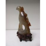 An early 20th century Chinese agate figure of a bird with wood stand, 13cm (5.25 in) high (2)