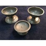 A pair of 18th century pewter salts and another, the pair with flat rims to rounded bowls on short