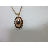 A garnet pendant and an associated Italian snake link chain, the pendant of pierced oval form with a