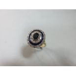 A diamond, sapphire and enamel oval target ring, the oval cut sapphire in a triple diamond-enamel-