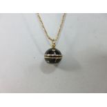 An enamelled pendant watch on a fancy link chain, the spherical watch enamelled in black and