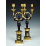 A pair of Regency bronze and ormolu two light candelabra, each of the branches curving from a ring