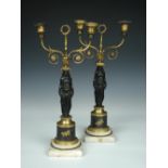 A pair of Regency bronze and ormolu candelabra, each with two lights curling up from a cushion on
