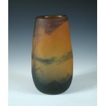 A cameo glass vase by Georges Raspiller, decorated with a lakeside landscape over a reddish orange