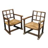 A pair of Cotswold School oak low elbow chairs, the lattice backs with swept arms and rush seats,
