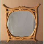 An Art Nouveau style carved beech wall mirror, the shaped plate glass with scrolling tendril