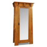 An Arts & Crafts oak single wardrobe, the tapering body with mirror panelled door 192 x 92 x 51cm (
