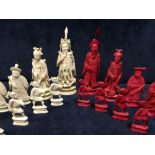 A Chinese red and white ivory part chess set, each piece carved as an appropriate figure, the