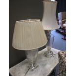 A glass table lamp together with another similar