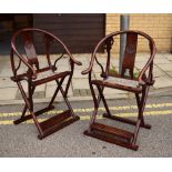 A pair of elm Mongolian folding chairs, each with horseshoe backs and with central roundels to the