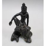 A bronze figure of Guanyin seated on a rock, her right hand holding a sacred pearl as her arm high
