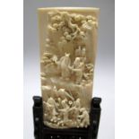 A 19th century ivory panel and a greenstone Buddhist lion with wood stands, the panel carved in