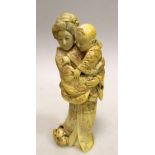 An early 20th century ivory group of a mother standing with child in arms watching a puppy at her