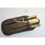 A small leather wallet containing three gold implements, comprising:- a 15ct gold mounted penknife