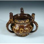 A Wrotham brown and yellow slip ware tyg/ puzzle jug, dated 1689 between the spire topped handles,