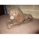 A mid-19th century brown saltglaze lion reclining on rectangular base, its tail end on its flank,