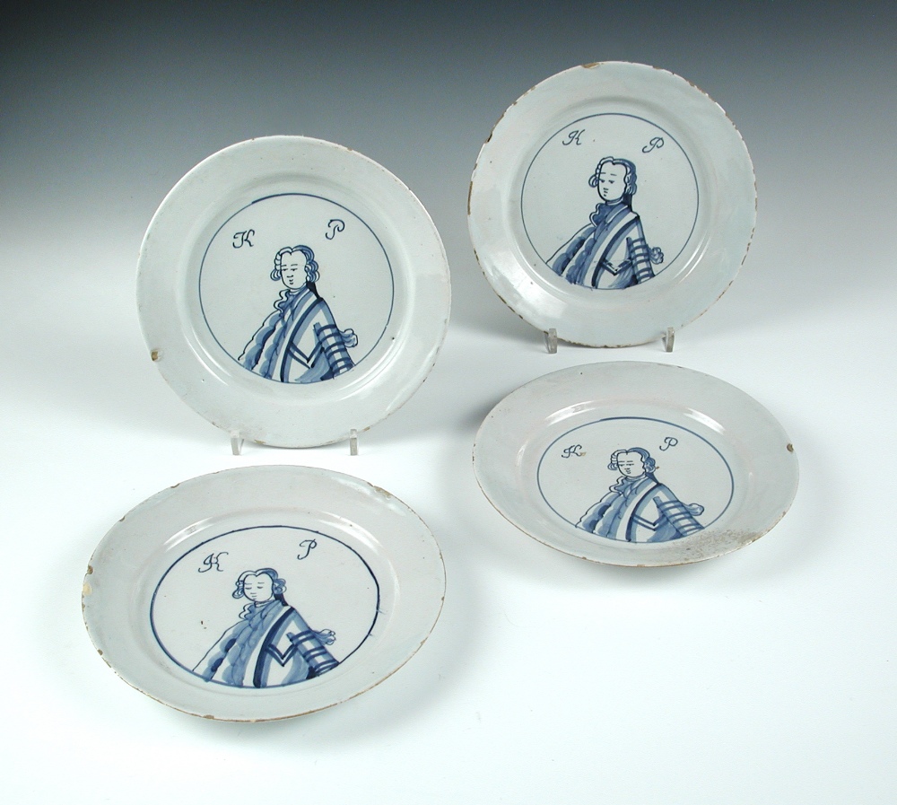 Four mid-18th century English Delft blue and white 'King of Prussia' plates, each painted with a