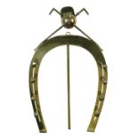 An early 20th century easel back horseshoe-shaped brass hunting whip rack, the horseshoe with four