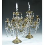 A pair of gilt metal and glass table lustres, early 20th century, each with facet cut shaped central