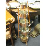 An ironwork stand and set of graduated polished copper saucepans