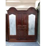 An Edwardian inlaid mahogany triple wardrobe with twin arched pelmet above a central two door