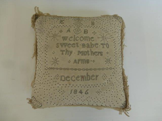 A Layette pin cushion, the pin heads displaying the inscription "Welcome sweet babe to tiny mother's