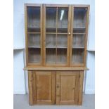 A Victorian waxed pine dresser, the glazed single door upper section above a panelled two door