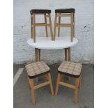 A circular formica topped drop flap kitchen table and four stools.