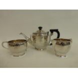 A silver three piece tea set comprising a teapot, milk jug and a twin handled sugar bowl, maker