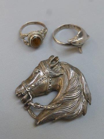 A silver and marcasite brooch in the form of a horses head, a silver dolphine ring and a silver