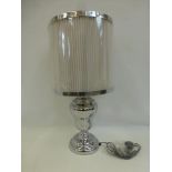 A large contemporary baluster table lamp with white pleated shade.