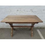 An oak refectory table of small proportions with X frame supports united by a stretcher.